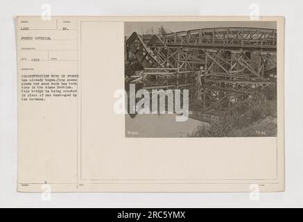 Reconstruction work being carried out in the Aisne section, which was heavily damaged by gunfire during World War One. This photograph displays the rebuilding process, with a new bridge being constructed to replace one destroyed by the Germans. Caption: 'Reconstruction work in progress in France, specifically in the Aisne section, to restore infrastructure damaged during the war.' Stock Photo