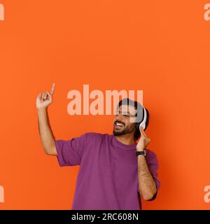 Thrilled young eastern guy enjoying his newest wireless headphones Stock Photo