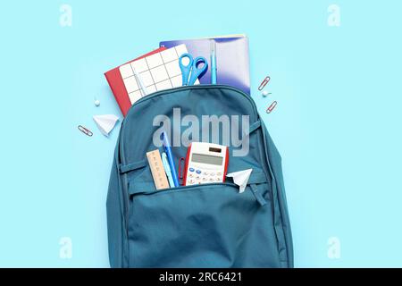 School backpack with different stationery on blue background Stock Photo