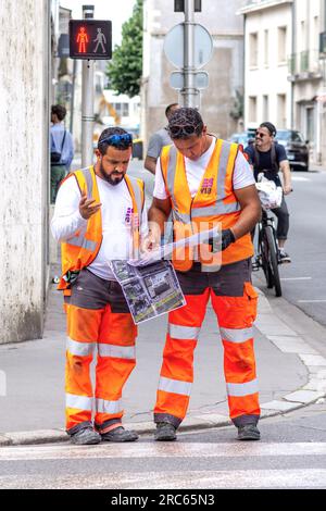 Council workmen looking at instructions for painting pedestrian crossing markings in city center - Tours, Indre-et-Loire (37), France. Stock Photo