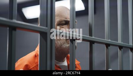 Angry prisoner standing behind bars Stock Photo - Alamy