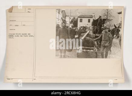 Italian soldiers take a break to get water along the Piave River in Italy during World War I. This photograph, taken in 1919, shows the troops pausing during their military activities. The image is part of the Photographs of American Military Activities collection, captured by Photogrammer Seed. The reference number for this picture is 111-SC-4047, with the Suret number being 10969. Stock Photo