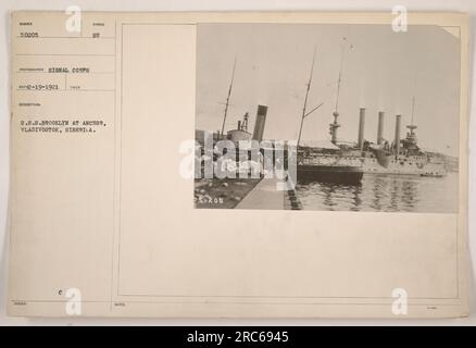 U.S.S. Brooklyn at anchor in Vladivostok, Siberia. The photograph was taken by the Signal Corps on February 19, 1921. It depicts the U.S.S. Brooklyn with a symbol attached. The note indicates that the photograph's identification number is 250205. Stock Photo