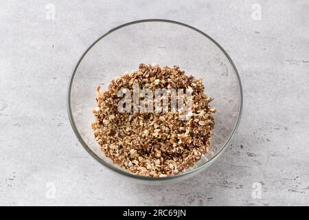 Glass bowl with mix of oatmeal, nuts, coconut sugar and dates on gray textured background, top view. Cooking delicious healthy oatmeal cookies. Stock Photo