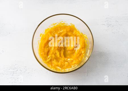 Glass bowl of pumpkin filling with cheese on a light blue background, top view. Cooking pumpkin casserole or pie. Stock Photo