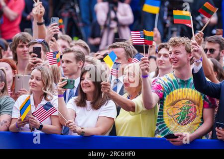 Vilnius, Lithuania. 12th July, 2023. People wave America and Lithuania flags as they watch U.S President Joe Biden deliver an address to the Lithuanian and Ukrainian nations at Vilnius University following the NATO Summit, July 12, 2023 in Vilnius, Lithuania. An estimated crowd of 10,000 people waved Lithuanian, American and Ukrainian flags and cheered the president. Credit: Adam Schultz/White House Photo/Alamy Live News Stock Photo