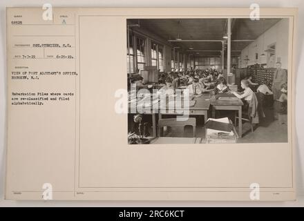A view of the Port Adjutant's Office in Hoboken, New Jersey. The office houses the Embarkation Files, where cards are re-classified and filed in alphabetical order. The photograph was taken on June 25, 1919, by Sot. Stemizer, S.C. and received on July 7, 1919. The description notes that there were 3,400 files in the office as of the time the photo was taken. Stock Photo