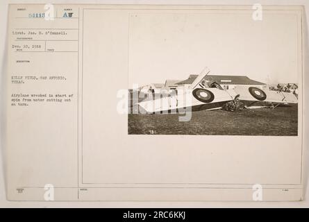 An airplane at Kelly Field in San Antonio, Texas, is seen wrecked during the start of a spin caused by the motor cutting out while making a turn. The photograph was taken on December 10, 1918, by Lieut. Jos. H. O'Connell. The image is cataloged under the subject number 54113, with additional notes stating its description and issue. Stock Photo