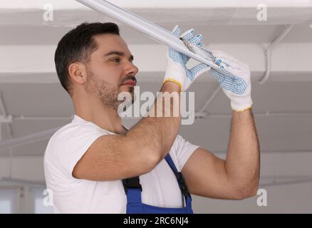 Ceiling light. Electrician installing led linear lamp indoors Stock Photo