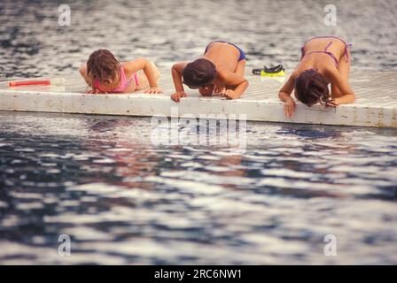 One boy and two girls having fun on a floating pier in a lake, Venezuela Stock Photo