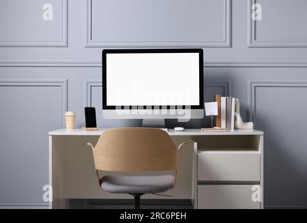 Cozy workspace with comfortable chair and computer on white desk indoors. Interior design Stock Photo