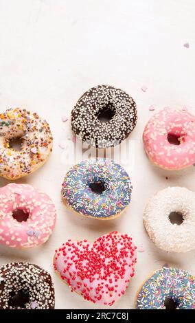 Donuts pattern. Top view of assorted glazed donuts. Colorful donuts with icing. Various colorful glazed doughnuts with sprinkles on a light background Stock Photo