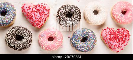 Donuts pattern. Top view of assorted glazed donuts. Colorful donuts with icing. Various colorful glazed doughnuts with sprinkles on a light background Stock Photo