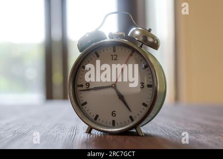 old mechanical alarm clock on wooden surface in a living room. vintage alarm clock on wooden table. don't oversleep. concept of time, deadline, it's t Stock Photo