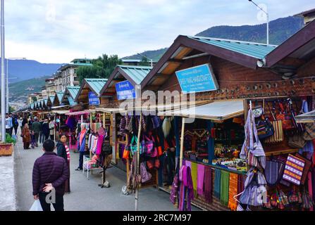 A row of identical shopping kiosks line a busy street in Thimphu, Bhutan. Local vendors sell clothing, jewelry, handicrafts, souvenirs and other items Stock Photo