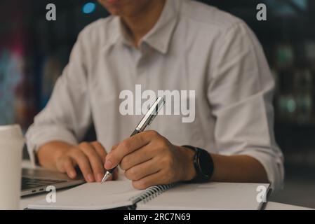 man hands with pen writing on notebook in the office.learning, education and work.writes goals, plans, make to do and wish list on desk. Stock Photo