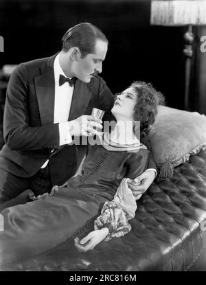 Hollywood, California:  1925 A scene in the early silent movie, 'Fifth Avenue Models, with actor Norman Kerry tending to an ill Mary Philbin. Stock Photo