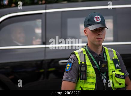 Lithuanian security policeman with US President Joe Biden waiving in the car in the background during Nato summit 2023 in the centre of Vilnius Stock Photo