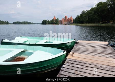 Wooden jetty with tourist boats on Lake Galve, in the background Trakai Castle Built in the 14th century and served as a residence for the Grand Dukes Stock Photo