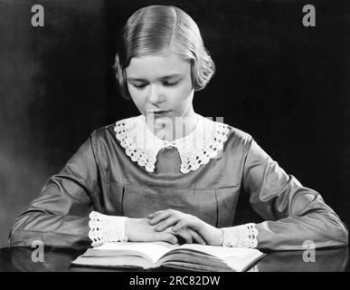 United States:  c. 1928 A teenage girl reading a book. Stock Photo