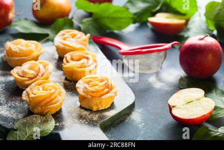 Apple Rose mini tarts with icing sugar on the stone cutting board. Stock Photo