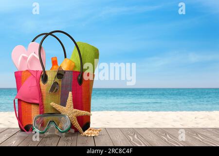Bag with scuba diving mask and accessories on sunny ocean beach, space for text. Summer vacation Stock Photo