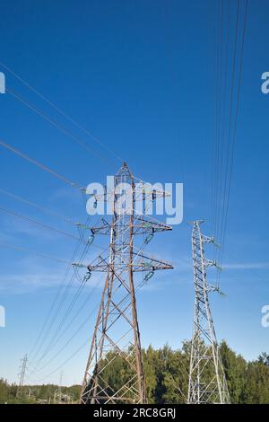 High voltage lines and power pylons against blue sky Stock Photo