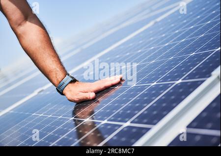 Engineer checking an operation of just installed solar battery. Close up view of hand on PV panel. Concept of reneweble energy. Stock Photo