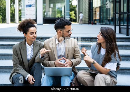 Group of business people walk outside in front of office buildings. Businessman and two businesswomen sharing experience ideas and tactic for successf Stock Photo