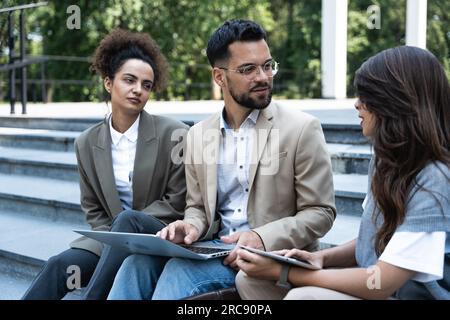 Group of business people walk outside in front of office buildings. Businessman and two businesswomen sharing experience ideas and tactic for successf Stock Photo