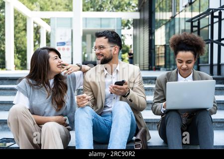 Group of business people walk outside in front of office buildings. Businessman and two businesswomen sharing experience ideas and tactic for successf Stock Photo