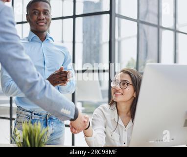happy Middle Eastern and African American partners using laptop computer at table desktop Stock Photo