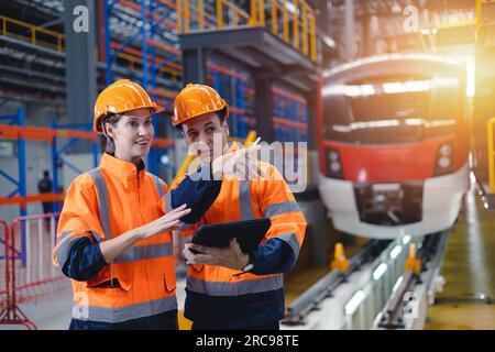 Engineer man and women worker working team together in electric train service depot transport industry factory technician mechanic staff. Stock Photo
