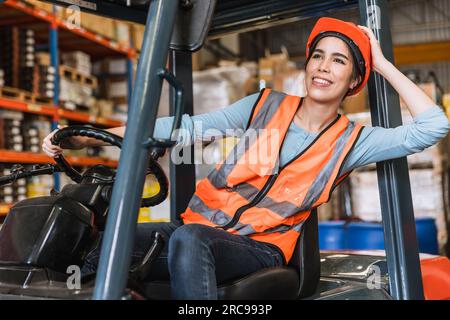 happy young teen warehouse staff worker enjoy smiling at forklift driver for control loading factory inventory shipping products Stock Photo