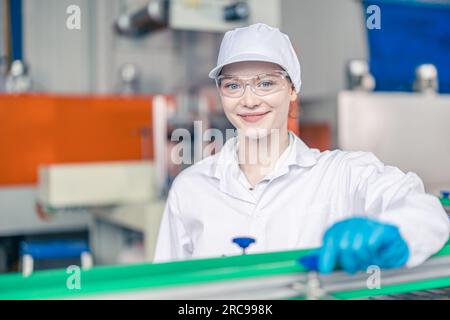 Processing Female Employee A woman employee in a beverage factory scrutinizes bottles on a ...