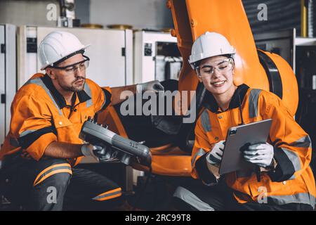 Happy engineer team working in modern automation factory with welding robot arm control training operation. women worker machine learning industry tec Stock Photo
