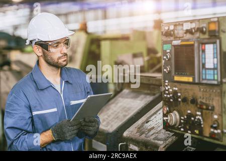 Hispanic latin indian male worker working control operate lathe CNC machine in heavy metal  steel factory Stock Photo