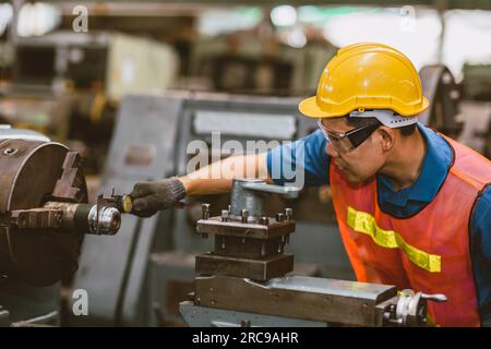 Young Asian Technician Engineer Staff Worker using Lathe CNC Milling Machine work in Heavy Metal Factory. Stock Photo