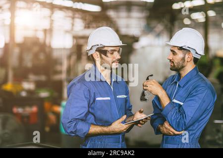 engineer worker male hispanic indian male teamwork happy working together in heavy metal industry steel lathe CNC factory Stock Photo