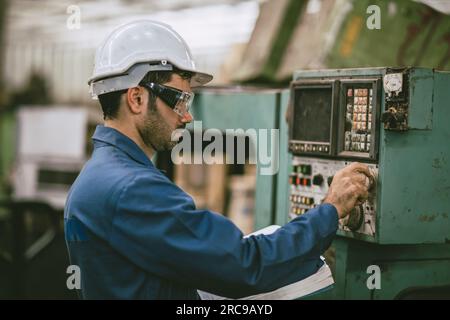 Hispanic latin indian male worker working control operate lathe CNC machine in heavy metal  steel factory Stock Photo