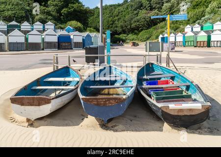 Middle Chine, Bournemouth, UK - July 12th 2023: Three rowboats on the beach in front of beach huts. Stock Photo