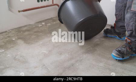Liquid floor for leveling the base. A worker uses epoxy concrete screed to level. Leveling with cement mix for floors. Pours a liquid self-leveling Stock Photo