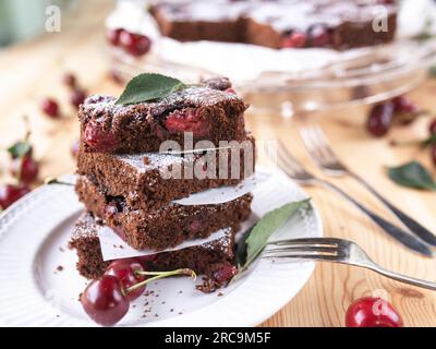 Chocolate cake with sour cherries on light wooden table. Top view Stock Photo