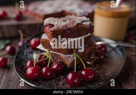 Chocolate cake with cherries on a black plate on wooden table Stock Photo