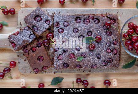 Chocolate cake with sour cherries on light wooden table. Top view Stock Photo