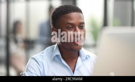 Thoughtful black man in eyeglasses stack with hard task, looking at computer screen, thinking of problem solution Stock Photo
