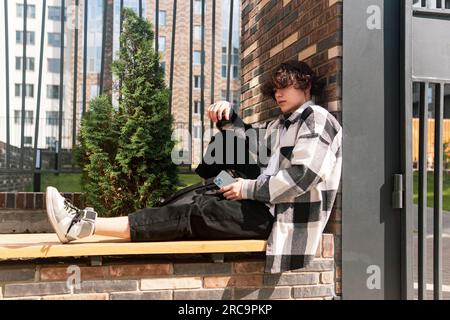 young man sits relaxed on a city bench Stock Photo