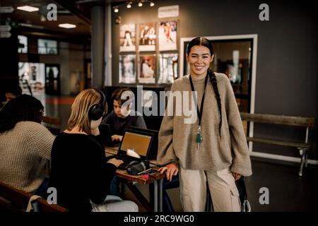 Portrait of smiling female teacher with students using laptops at high school Stock Photo