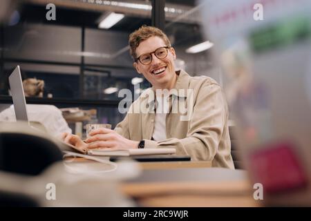 Happy businessman using laptop at desk in office Stock Photo