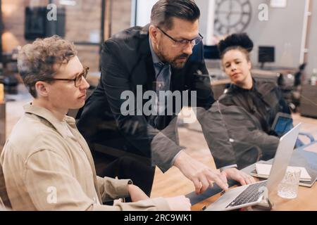Manager using laptop while discussing with businessman in office Stock Photo